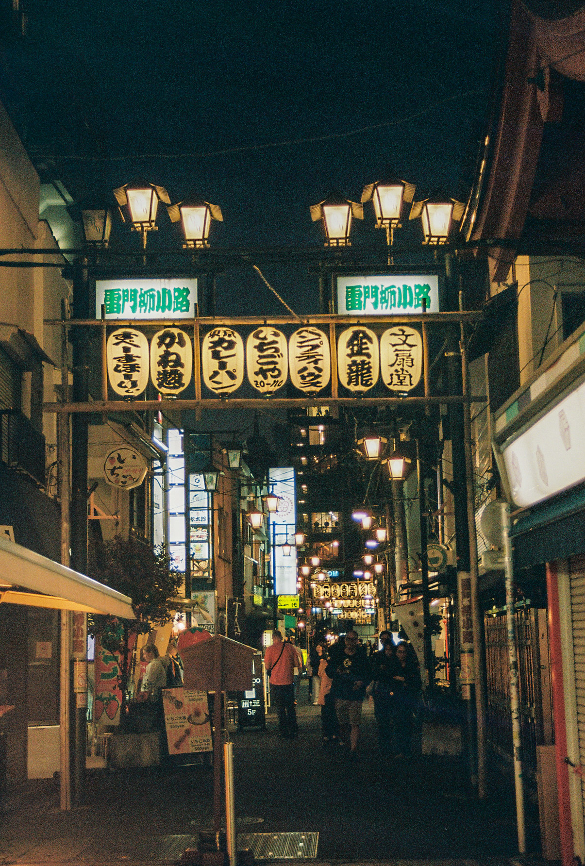 Paper lanterns glowing at the entrance of Kaminarimon Yokocho at night
