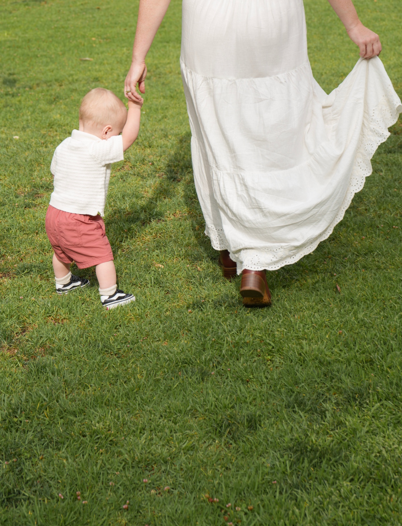 Mother and child walking hand in hand across the grass