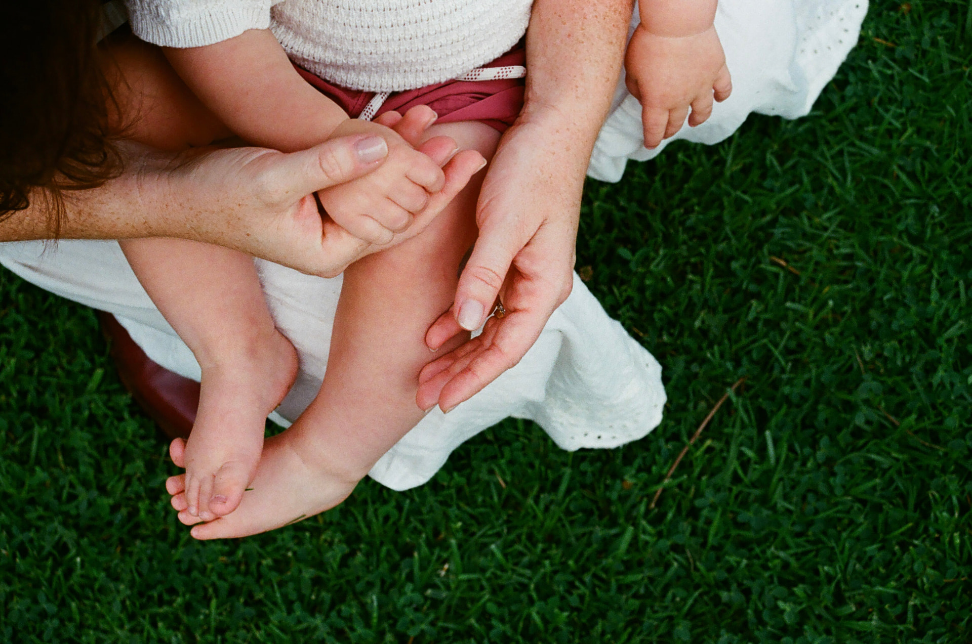 Mother and baby's hands and feet in the grass