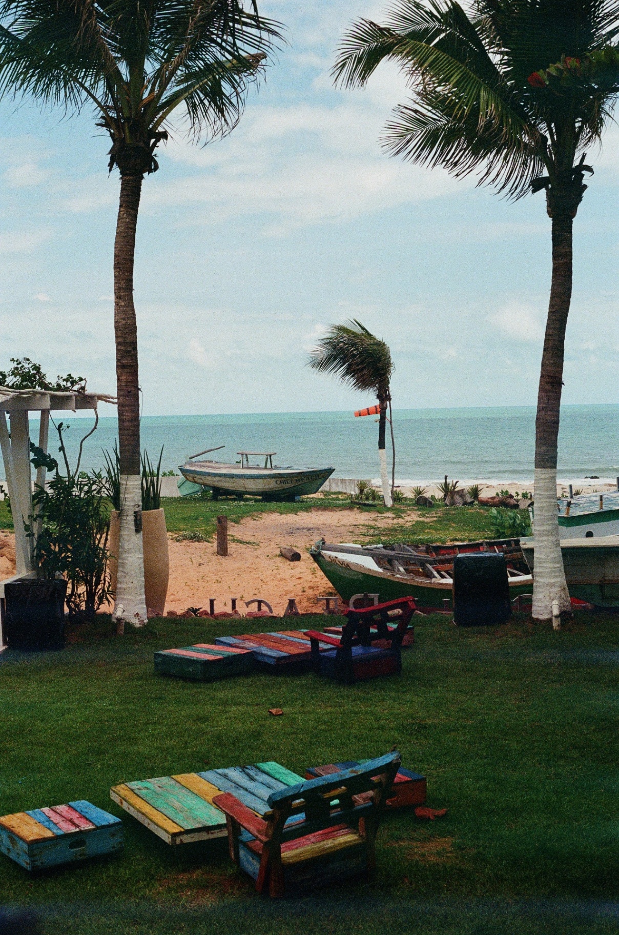 Palms, painted pallet chairs and fishing boats at Chili Beach