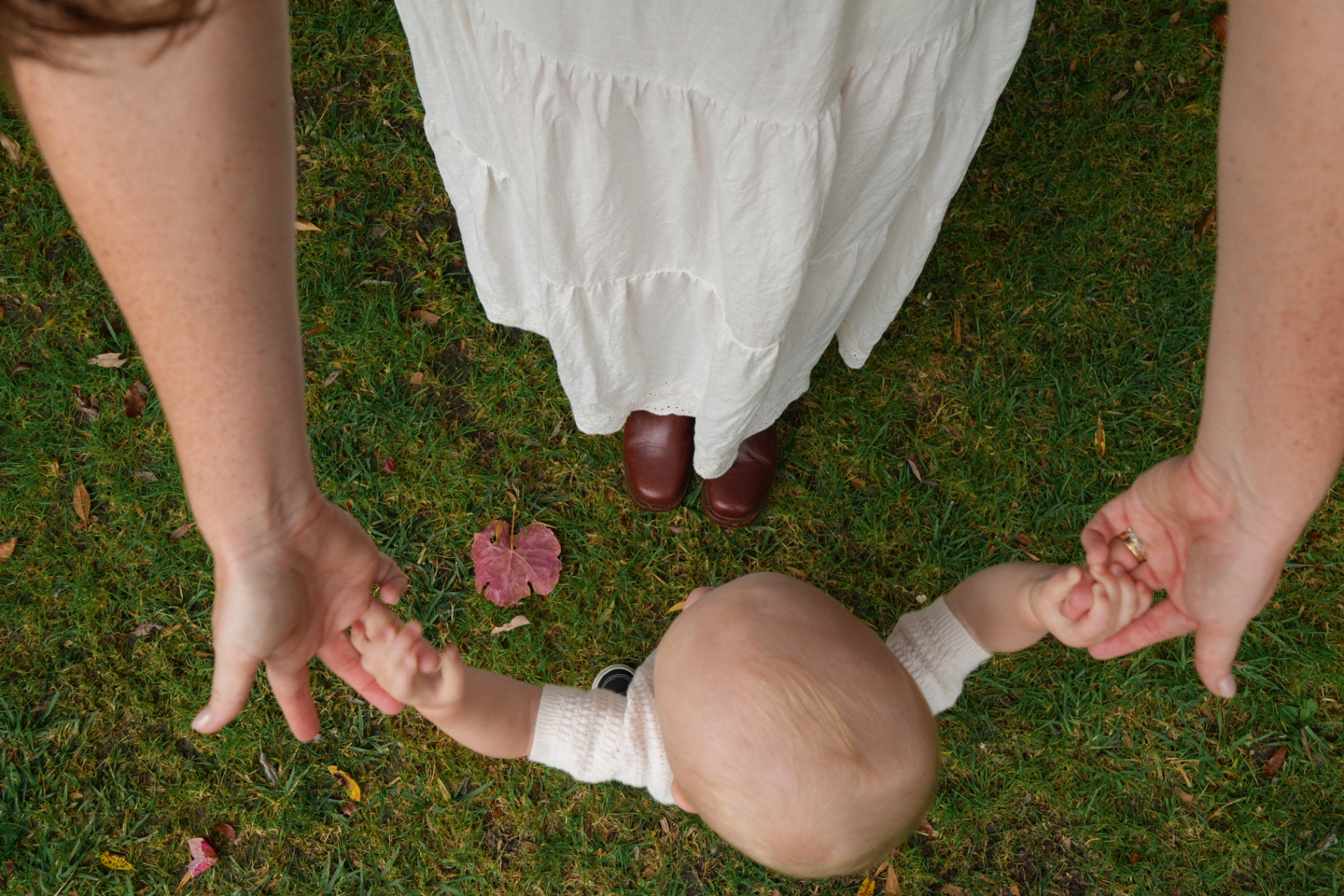 Overhead of a baby reaching up to hold both of a mother's hands