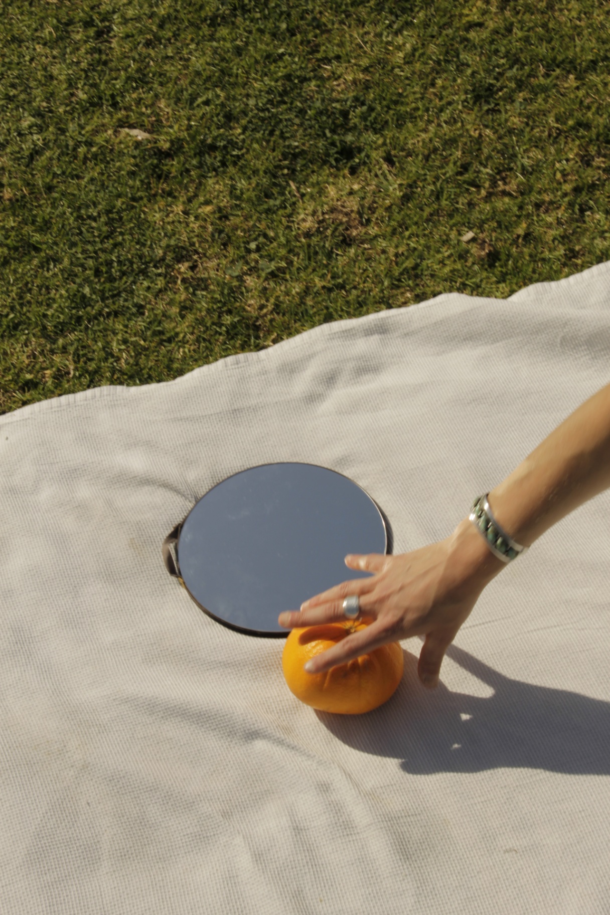 Mirror and orange on a picnic blanket