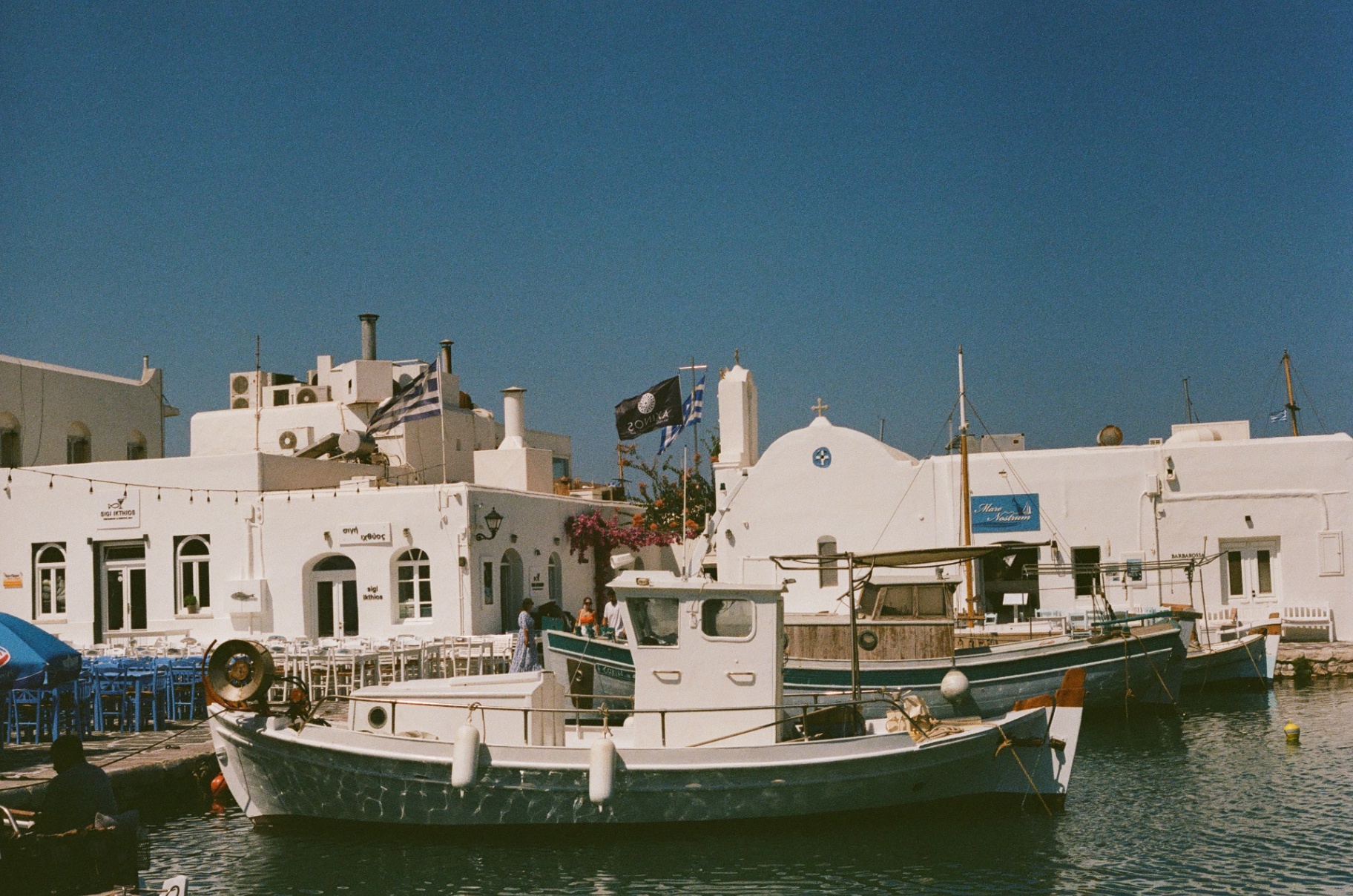 A fishing boat at rest in a whitewashed Greek harbor