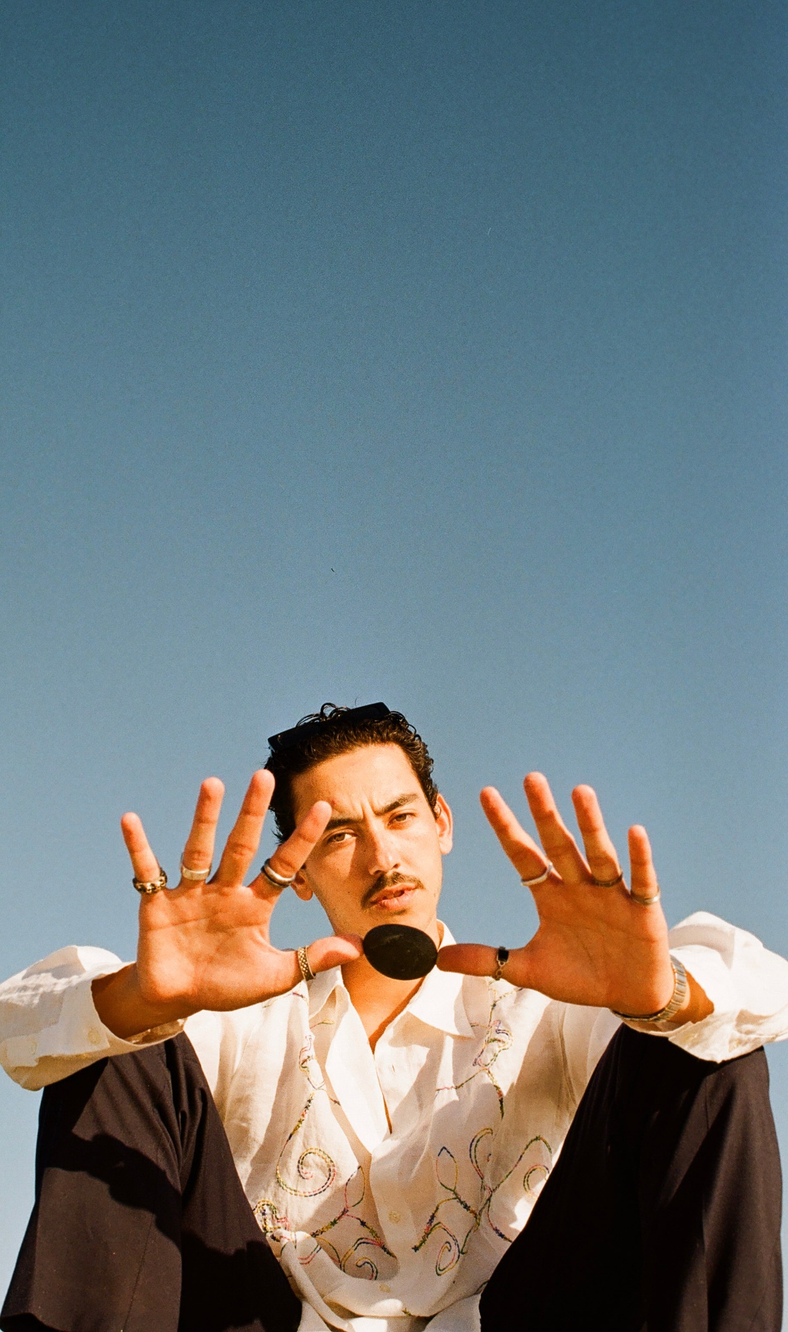 Portrait with hands raised against a clear blue sky