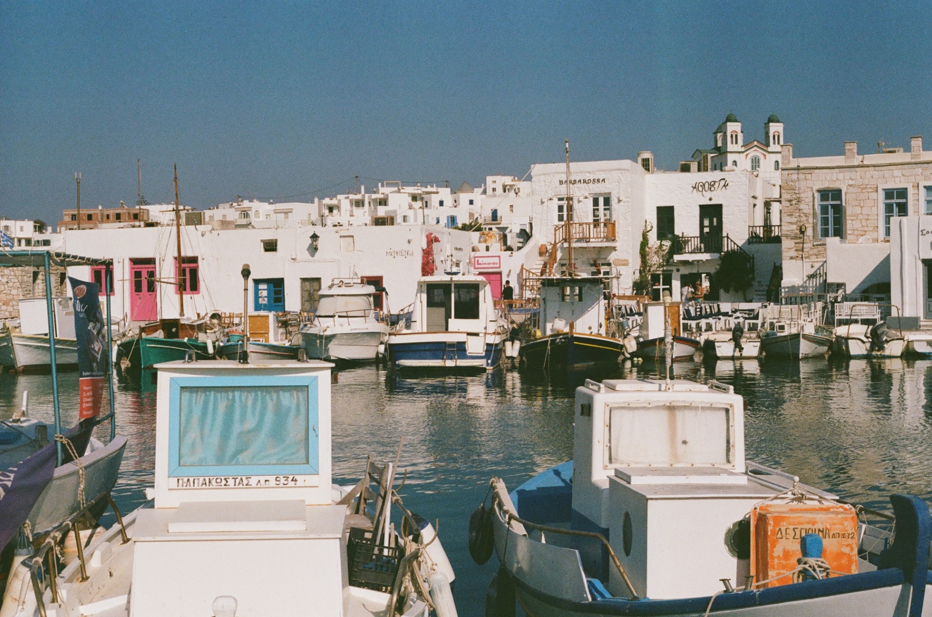 Boats lined up in a sunlit Paros harbor