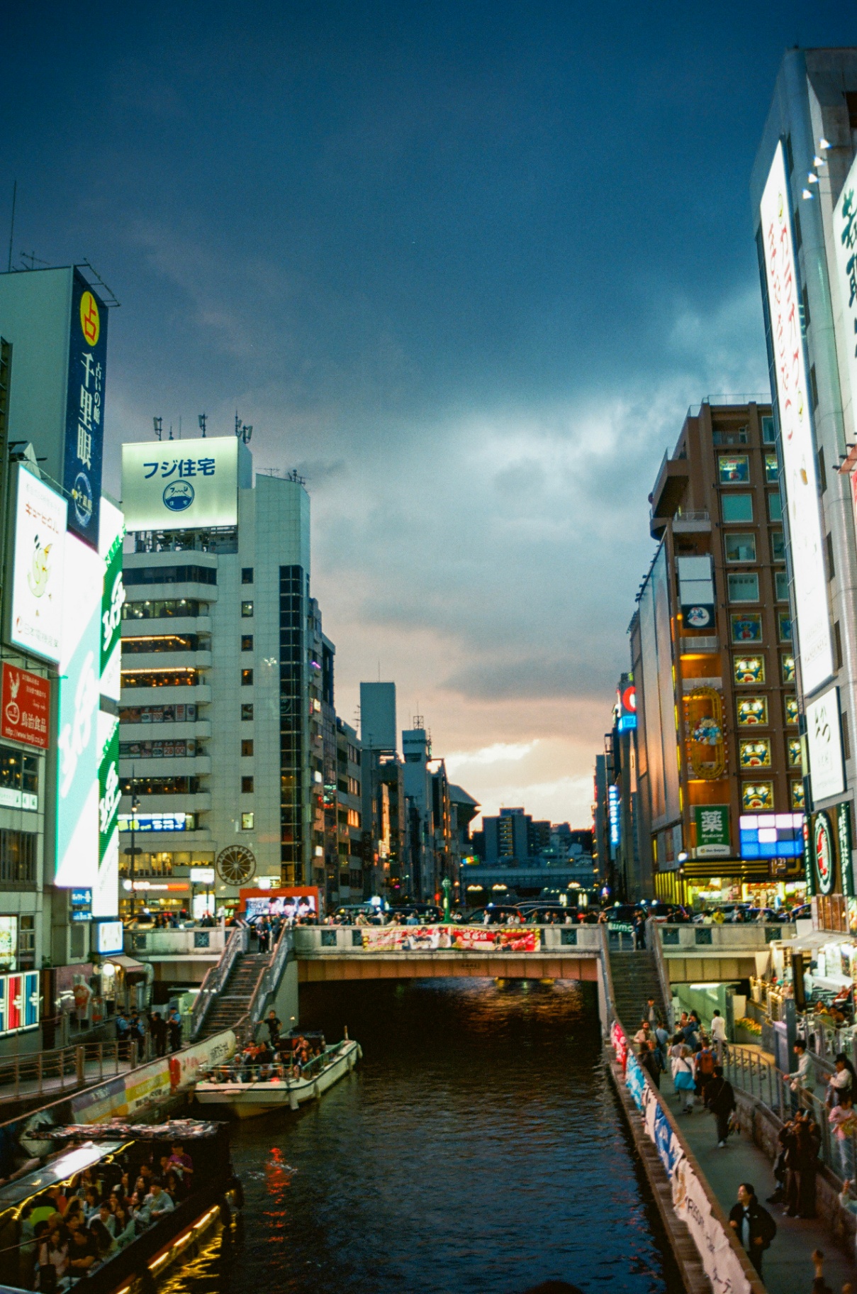 The Dōtonbori canal at dusk with tour boats and neon signs