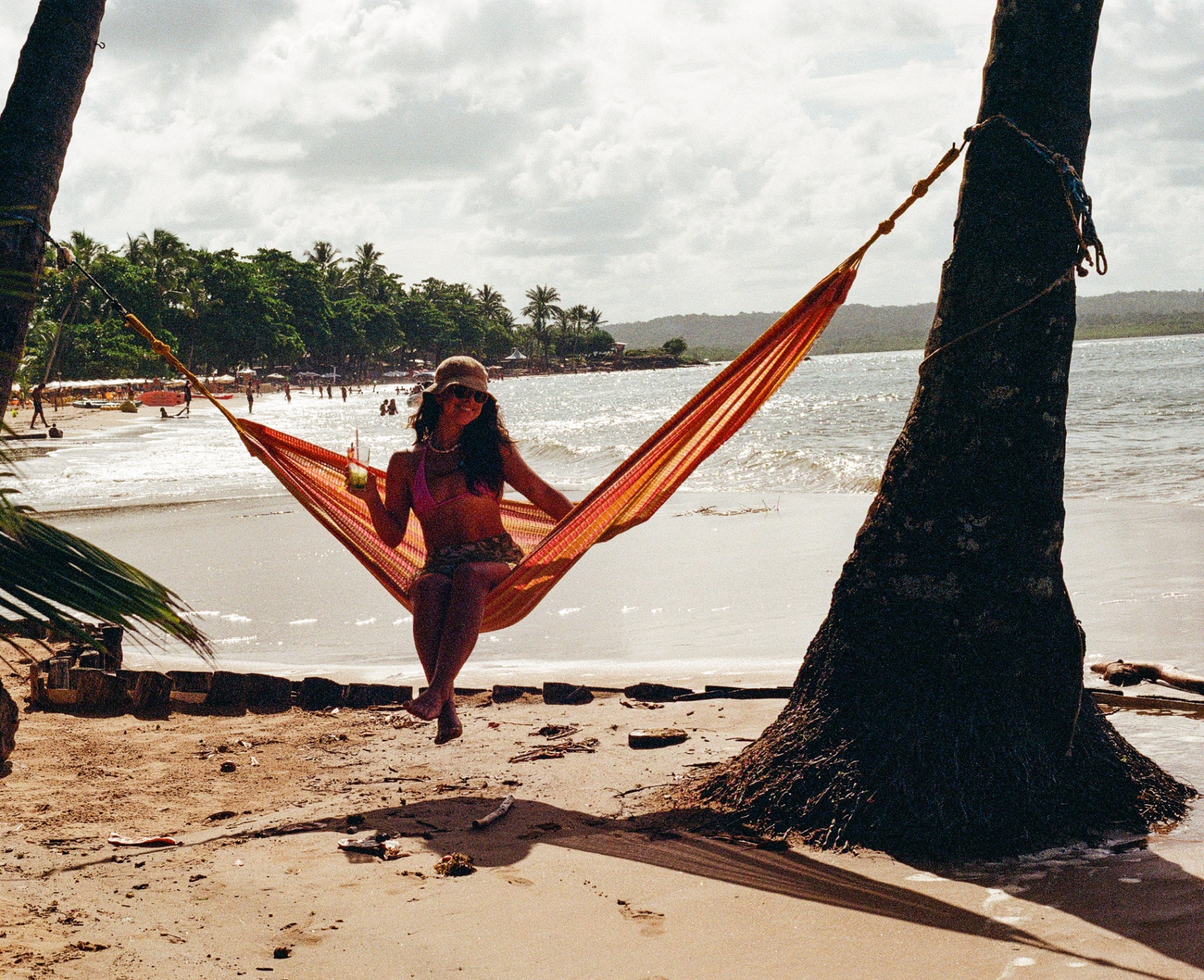 Woman relaxing in a striped hammock between palm trees on a Brazil beach
